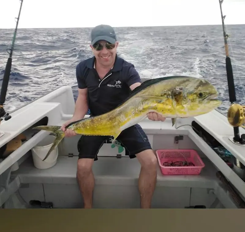 Un client tient une dorade coryphène à bord de FreeDom