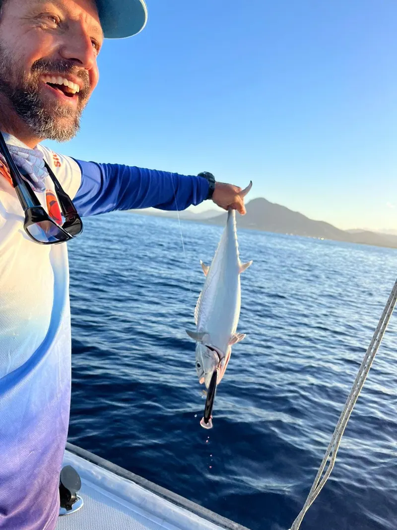 Dominique, souriant, tient sa prise à bout de bras