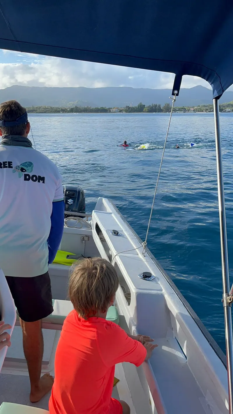 Un enfant à l’avant de FreeDom regarde la mer, Dominique à la barre