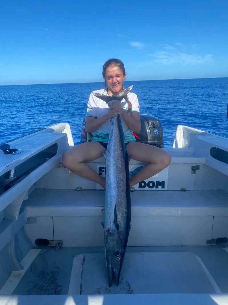 Une jeune pêcheuse assise à l’arrière de FreeDom, un thazard dans les bras